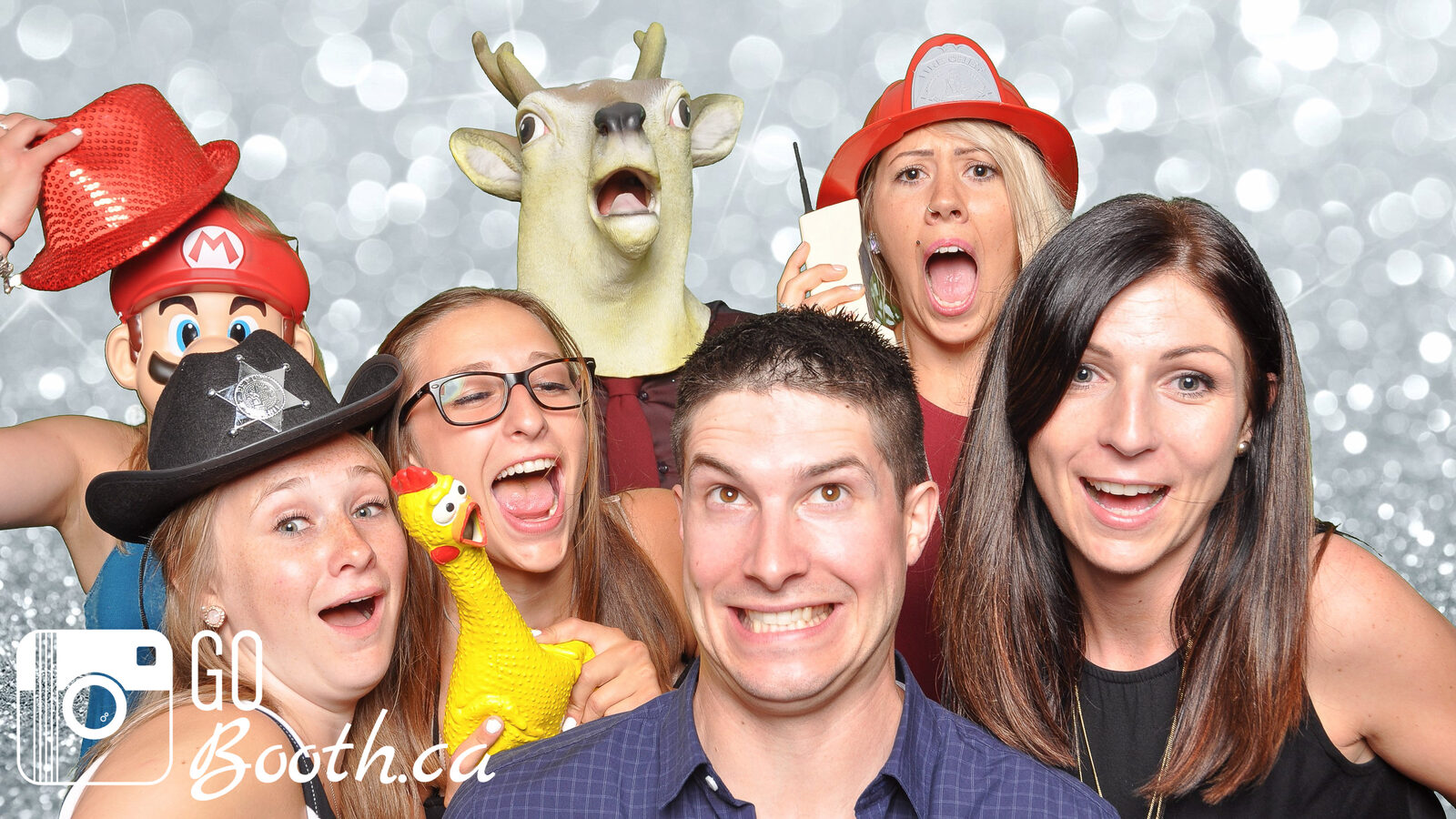 Guests with props laughing in front of a silver sequin backdrop